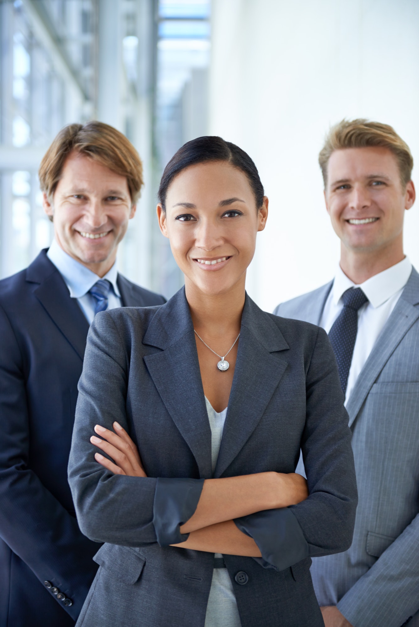 Portrait of three smiling executives standing in an office lobby